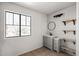 Bathroom with a gray vanity, wooden shelves, circular mirror, and a window overlooking the outdoors at 15611 W Cameron Dr, Surprise, AZ 85379