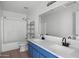 Bathroom featuring a blue vanity with double sinks, a large mirror, and a shower with a glass door at 15611 W Cameron Dr, Surprise, AZ 85379