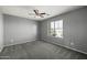 Cozy carpeted bedroom with a ceiling fan and bright natural light from a window at 15611 W Cameron Dr, Surprise, AZ 85379
