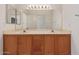 Bathroom featuring a double sink vanity with wood cabinets and a large mirror at 15980 W Quail Creek Ln, Surprise, AZ 85374