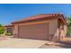 Double garage of a cozy home featuring desert landscaping, rock accents, and a clay tile roof at 15980 W Quail Creek Ln, Surprise, AZ 85374