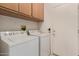 Laundry room with washer, dryer, cabinets for storage, and a white door for access to outside at 15980 W Quail Creek Ln, Surprise, AZ 85374
