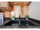 Close-up of a black kitchen sink with granite countertop and copper backsplash at 1844 W Virginia Ave, Phoenix, AZ 85007
