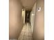 The hallway has neutral colored walls, tiled floor and a light fixture. There is a door at the end at 3937 W Stella Ln, Phoenix, AZ 85019