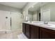 Bathroom featuring a walk-in shower, double sink vanity, tile flooring, and a large mirror at 40913 W Williams Way, Maricopa, AZ 85138