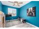Bedroom with striking blue walls, ceiling fan, window with shutters, and tile flooring at 40913 W Williams Way, Maricopa, AZ 85138