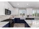 Modern kitchen featuring navy and white cabinetry, marble countertops, and stainless steel appliances at 40913 W Williams Way, Maricopa, AZ 85138