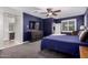 Bright main bedroom with carpet, shutters, large TV, and a Primary bath nearby at 40913 W Williams Way, Maricopa, AZ 85138
