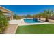 Backyard pool featuring green grass, palm trees, and a tanning ledge with a blue umbrella for outdoor relaxation at 40913 W Williams Way, Maricopa, AZ 85138