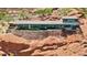 Stunning home boasts a sleek, glass-walled design with a stone base, nestled into a red rock hillside at 4925 E Red Rock Dr # 43, Phoenix, AZ 85018
