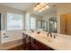 Bathroom featuring dual sinks, a large tub, and natural lighting at 888 S 165Th Ln, Goodyear, AZ 85338