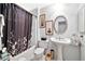 Bathroom with white pedestal sink, toilet, and shower-tub with shower curtain at 10205 W Royal Oak Rd, Sun City, AZ 85351