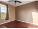 Empty bedroom featuring a ceiling fan, hardwood floors, large window with curtain, and neutral paint at 2062 W Roy Rogers Rd, Phoenix, AZ 85085