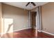 Empty bedroom featuring a ceiling fan, hardwood floors, with sunlight streaming from an open door at 2062 W Roy Rogers Rd, Phoenix, AZ 85085