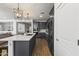 Angle view of the modern kitchen boasts wood floors, stainless appliances, gray cabinets, and an island with white countertop at 22657 N 184Th Ln, Surprise, AZ 85387
