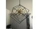 Modern black and gold geometric chandelier with Edison bulbs, complemented by neutral blinds at 8673 W Palm Ln, Phoenix, AZ 85037