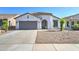 Charming single-story home with desert landscaping, covered entry, and gray two car garage door at 1120 W Desert Hollow Dr, San Tan Valley, AZ 85143