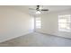 Large bedroom with plush carpeting, ceiling fan, neutral walls, white trim, and bright natural light at 12813 W Paradise Dr, El Mirage, AZ 85335