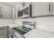 Updated kitchen featuring a stainless steel stove, microwave, gray cabinets with black hardware, and quartz counters at 12813 W Paradise Dr, El Mirage, AZ 85335
