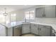 Updated kitchen featuring gray cabinets, quartz countertops, stainless steel sink and faucet, and tile backsplash at 12813 W Paradise Dr, El Mirage, AZ 85335