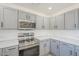 Bright kitchen featuring new stainless steel appliances, quartz counters, sleek gray cabinets, and hardwood floors at 12813 W Paradise Dr, El Mirage, AZ 85335