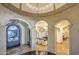 Grand foyer with stone archways, wrought iron door, chandelier, and stone floors, creating an elegant entry at 13074 E Saddlehorn Trl, Scottsdale, AZ 85259