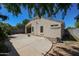 Exterior view of the home with a covered patio and a block-walled backyard with patio and green trees at 13959 W Country Gables Dr, Surprise, AZ 85379
