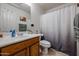 Well-lit bathroom with a functional single sink vanity, toilet, and shower with a decorative curtain at 13959 W Country Gables Dr, Surprise, AZ 85379