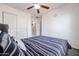 Cozy bedroom featuring a double closet, ceiling fan, and calming striped bedding with modern gray floors at 13959 W Country Gables Dr, Surprise, AZ 85379
