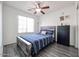Bright bedroom with a large window, modern ceiling fan, light gray flooring, and contemporary furnishings at 13959 W Country Gables Dr, Surprise, AZ 85379
