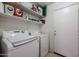 Practical laundry room with a washer, dryer, and ample shelf space for storage, next to a door at 13959 W Country Gables Dr, Surprise, AZ 85379