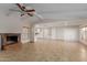 Open living room with fireplace, ceiling fan, neutral tile flooring, and an open view to the kitchen at 3433 E Betty Elyse Ln, Phoenix, AZ 85032