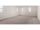 A bedroom features neutral carpet, white walls, and multiple windows allowing natural light at 36025 W Santa Clara Ave, Maricopa, AZ 85138