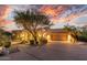 Elegant home exterior with a circular driveway, mature trees, and landscape lighting enhances curb appeal at twilight at 10119 E Winter Sun Dr, Scottsdale, AZ 85262