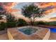 Backyard featuring a hot tub surrounded by mature landscaping at sunset at 10119 E Winter Sun Dr, Scottsdale, AZ 85262