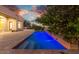 Illuminated pool at dusk lined with custom brick, surrounded by greenery at 10119 E Winter Sun Dr, Scottsdale, AZ 85262