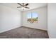 Bright, empty bedroom with carpet and neutral walls that offers a view of the neighborhood at 13529 W Remuda Dr, Peoria, AZ 85383