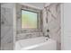 Elegant bathroom with a soaking tub surrounded by marble-like tile and a window with a backyard view at 15131 W Melissa Ln, Surprise, AZ 85374