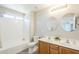 A bathroom with a shower/tub combination, commode, and double sink vanity with wood cabinets at 15205 N Honcho Ct, El Mirage, AZ 85335