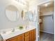 Bathroom with a dual sink vanity, decorative mirrors, lighting and an open doorway to closet at 15205 N Honcho Ct, El Mirage, AZ 85335
