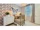 Charming Bedroom features a gold crib, decorative wallpaper, white dresser and natural light at 16743 W Charlotte Dr, Surprise, AZ 85387