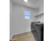 Modern laundry room with gray appliances, a window for natural light, and tiled floors at 21262 E Cherrywood Dr, Queen Creek, AZ 85142