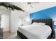Bedroom with blue accent wall features bed, vaulted ceiling with ivy, and entrance to the en suite bathroom at 3550 E Edna Ave, Phoenix, AZ 85032