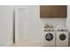 Efficient laundry room with modern washer, dryer, and overhead storage cabinets at 3703 E Gold Mountain Ave, San Tan Valley, AZ 85143