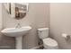 Powder room features pedestal sink, neutral color palette, and large mirror at 42424 N Gavilan Peak Pkwy # 57104, Anthem, AZ 85086