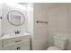 Modern half-bathroom with white vanity, round mirror, and sleek black fixtures at 44538 W Canyon Creek Dr, Maricopa, AZ 85139