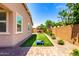 Backyard featuring artificial grass, a dining set with an umbrella, and colorful flowers at 45424 W Norris Rd, Maricopa, AZ 85139