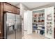 Open pantry area next to stainless steel refrigerator, providing ample storage at 45424 W Norris Rd, Maricopa, AZ 85139