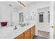 Bright bathroom with dual sinks, wood cabinets, a large mirror, and a door leading to a separate toilet room at 5529 E Holmes Ave, Mesa, AZ 85206
