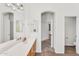 Bright bathroom featuring double sinks, light wood cabinets, and an arched doorway, with neutral walls and floors at 5529 E Holmes Ave, Mesa, AZ 85206